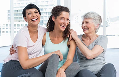 three woman are laughing and embracing while seated on the floor